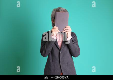 Le professeur asiatique senior debout sur fond vert. Banque D'Images