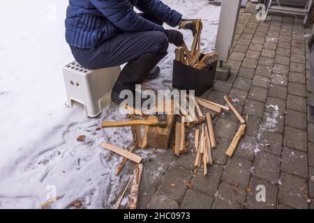 Vue rapprochée de l'homme rassemblant des copeaux de bois hachés pour la cheminée dans une boîte noire.Suède. Banque D'Images