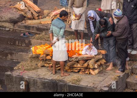 Le principal deuil met du riz dans la bouche du défunt lors de la cérémonie de crémation à Pashupatinath, Katmandou, Népal. Banque D'Images