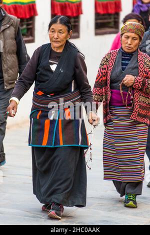 Les réfugiées tibétaines aux perles de prière de mala contournent les ambulances autour de la Boudhanath Stupa, Katmandou, Népal. Banque D'Images