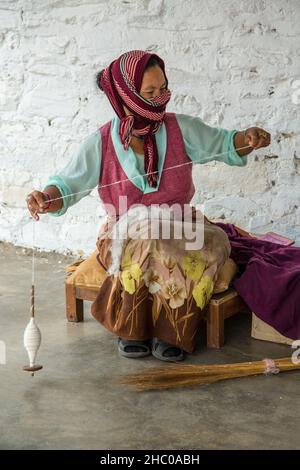 Une réfugiée tibétaine transforme la laine en fils à la main pour faire des tapis dans un village de réfugiés de Pokhara, au Népal. Banque D'Images