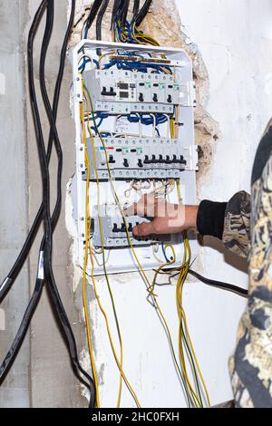 Un électricien installe un panneau électrique dans la maison.La conduite de l'électricité, la mise sous tension et la protection.Russie, Anapa - 11.07.2020 Banque D'Images