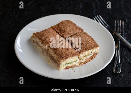 Baklava froide sur fond sombre.Dessert turc sucré. Assiette de gâteau aux fruits de la forêt en tranches.Assiette de baklava de lait froid.Boulangerie méditerranéenne. Banque D'Images