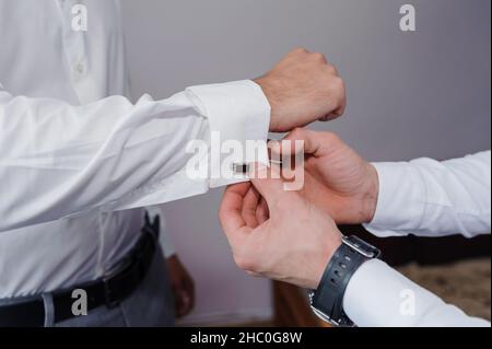 Homme attachant un lien de manchette sur la chemise.Le marié fixe les boutons de manchette sur la chemise Banque D'Images