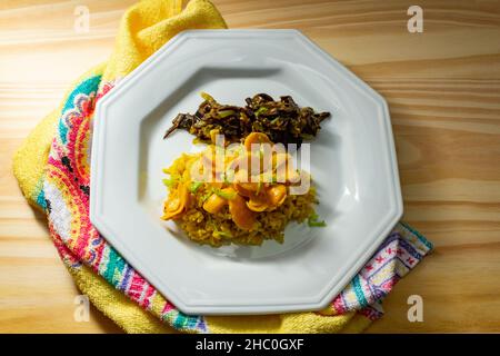 Goias, Brésil – 22 décembre 2021 : plat blanc avec riz à la pulpe de pequi et viande à la banane.Nourriture végétalienne.Pequi est un fruit typique de Banque D'Images