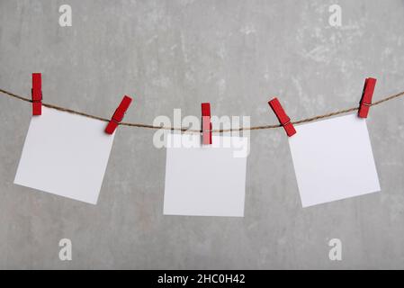 Des feuilles de papier vierges sont suspendues avec des épingles à linge sur la corde.Place pour votre texte.Copier l'espace. Banque D'Images