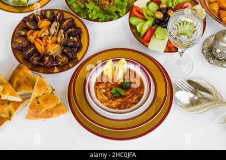 Dîner traditionnel au Ramadan - Menu Iftar conçu avec de la vaisselle élégante ; soupe, fruits secs, salade, pain et eau. Banque D'Images