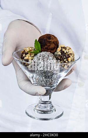 Garçon tenant des boules de fruits de palmier sur son uniforme de couleur blanche. Banque D'Images