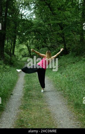 blonde marche à travers les bois, porte un t-shirt turquoise. la fille danse Banque D'Images