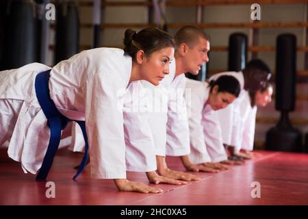 Groupe multiracial d'hommes et de femmes qui font des push-up dans la salle de gym Banque D'Images