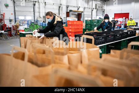 22 décembre 2021, Berlin: Celina Räder (l) et Amélie Tempel mettent de la nourriture dans des sacs en papier dans une salle du Berliner Tafel sur le marché de gros de Berlin.Actuellement, près de 40 000 aides emballez chaque jour plus de 1 000 colis de Noël pour les nécessiteux et les sans-abri.Environ 8 000 de ces sacs bien remplis sont distribués par les institutions sociales pendant la saison de Noël.Mais : par rapport aux années précédentes, le Tafel de Berliner souffre d'un énorme déclin des dons alimentaires.Les grandes chaînes de vente au détail vendent maintenant jusqu'à 99 % de leur nourriture.Cela laisse moins pour les nécessiteux.(À dpa 'Tafel reçoit moins de dons Banque D'Images