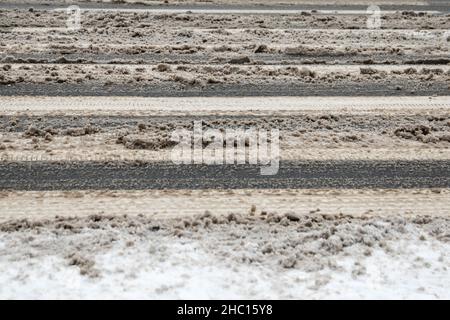 Passage piéton enneigé, glissant et boueux.Épandage de sel sur la route. Banque D'Images