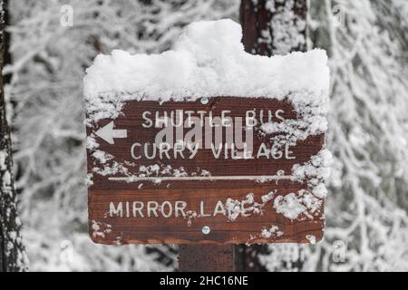 Bus-navette/panneau du village de Curry couvert de neige après la tempête dans le parc national de Yosemite. Banque D'Images