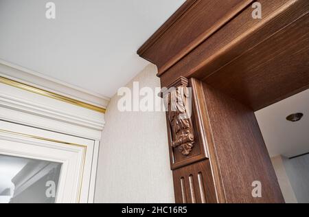 Porte en bois décorée avec des supports de mobilier sculptés et panneau cannelé près d'un présentoir vintage avec porte en verre dans un style classique, clair et spacieux Banque D'Images