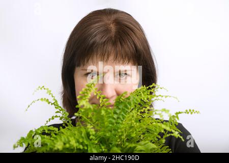 Portrait d'une jeune femme aux cheveux sombres avec une fleur de couleur vert vif dans les mains.Gros plan.Isolé sur fond blanc Banque D'Images