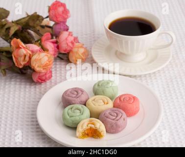 Biscuits colorés en forme de fleur servis avec une tasse de café sur un tissu blanc Banque D'Images