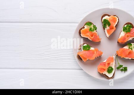 Mini sandwiches avec du saumon, du fromage caillé, du persil et du pain de seigle sous forme de coeurs.Saint-Valentin cuisine créative maison.J'adore le design du petit déjeuner.Séle Banque D'Images