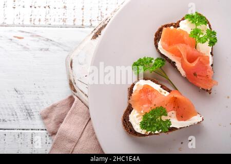 Mini sandwiches avec du saumon, du fromage caillé, du persil et du pain de seigle sous forme de coeurs.Saint-Valentin cuisine créative maison.J'adore le design du petit déjeuner.Séle Banque D'Images