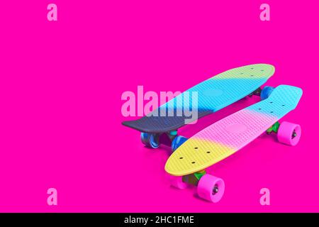 Deux planches à roulettes en plastique arc-en-ciel Penny sur fond de cramoisi Banque D'Images