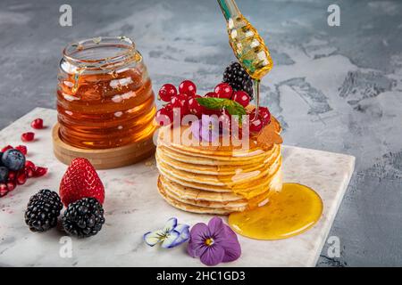 Crêpes.Petit déjeuner sain d'été, crêpes américaines classiques maison avec baies fraîches et miel, matin gris clair pierre fond de copie espace v Banque D'Images