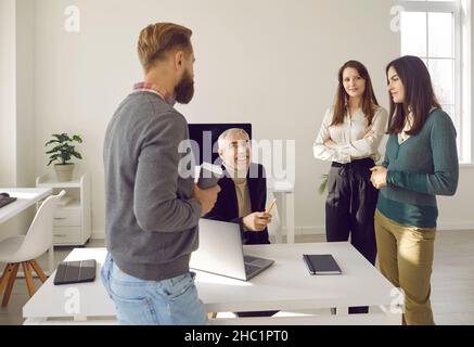 Divers collègues ayant des conversations informelles sur le lieu de travail au bureau pendant les pauses. Banque D'Images