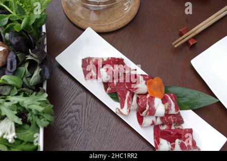 Tranches de rouleaux de bœuf cru pour le hot pot sur la plaque blanche Banque D'Images