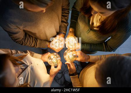 Équipe de personnes tenant des ampoules électriques illustrant le concept de l'idée créative et de l'innovation Banque D'Images