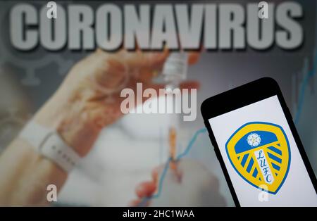 Photo du dossier datée du 09-01-2021 du logo Leeds United football Club affiché sur un téléphone portable avec une illustration du coronavirus sur un moniteur en arrière-plan.Le match de Liverpool contre Leeds et le match de Wolves contre Watford le lendemain de Noël ont été mis fin à cause d’infections à coronavirus, a annoncé la Premier League.Date d'émission : jeudi 23 décembre 2021. Banque D'Images