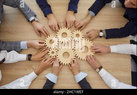 Les hommes d'affaires empilent des engrenages en bois les uns à côté des autres, ce qui symbolise le travail d'équipe et le succès. Banque D'Images