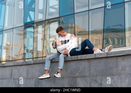 Une fille souriante a mis la tête sur les genoux de son petit ami.Guy regardant sa petite amie.Jeune couple dans la ville.Date romantique. Banque D'Images