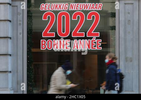 Bruxelles, Belgique.21st décembre 2021.Les gens marchent devant une fenêtre avec les mots "bonne année 2022" à Bruxelles, Belgique, le 21 décembre 2021.Selon le microbiologiste Emmanuel Andre, la Belgique est au milieu d'une nouvelle vague de pandémie de COVID-19 due à la variante Omicron, qui représentait 20 pour cent de tous les résultats positifs des tests effectués dans tout le pays lundi matin.Credit: Zheng Huansong/Xinhua/Alay Live News Banque D'Images