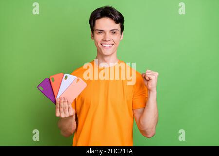 Photo du jeune heureux joyeux gagnant bonne humeur tenir les mains téléphones étuis isolés sur fond vert Banque D'Images