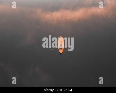 Photo aérienne d'un homme ramer un bateau.Nuages qui se réfléchissent à la surface du lac.Photo de drone. Banque D'Images