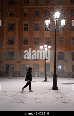 Homme marchant le long de la neige vide nuit ville rue après la tempête de neige lourde en hiver Banque D'Images