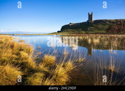 Château de Dunstanburgh Northumberland Angleterre se reflète dans un bassin d'eau de mer Embleton Bay Northumberland côte Angleterre GB Royaume-Uni Europe Banque D'Images