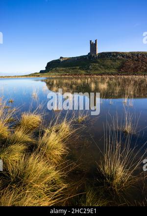 Château de Dunstanburgh Northumberland Angleterre se reflète dans un bassin d'eau de mer Embleton Bay Northumberland côte Angleterre GB Royaume-Uni Europe Banque D'Images