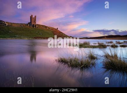 Château de Dunstanburgh Northumberland Angleterre se reflète dans un bassin d'eau de mer Embleton Bay Northumberland côte Angleterre GB Royaume-Uni Europe Banque D'Images