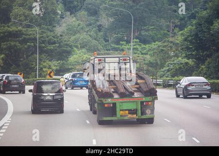 Un camion-remorque qui se déplace sur la route transporte de longs aciers sur la route jusqu'à la prochaine destination de déchargement. Singapour. Banque D'Images