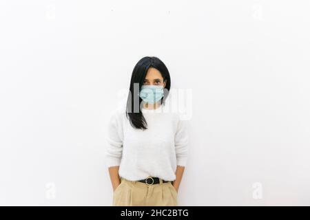 Jeune femme caucasienne aux cheveux longs est isolée avec assurance par le mur blanc de fond. Banque D'Images