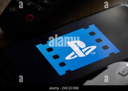 Rheinbach, Allemagne, 5 juin 2021, Vue rapprochée du logo « PlayStation Video » sur l'écran d'un smartphone avec deux télécommandes Banque D'Images