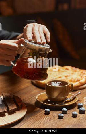 le gars tient la bouilloire et verse le thé chaud dans la tasse. café. mains de l'homme Banque D'Images