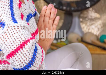 Femme vêtue de blanc pratiquant le yoga kundalini assis sur le sol et les mains ensemble Banque D'Images