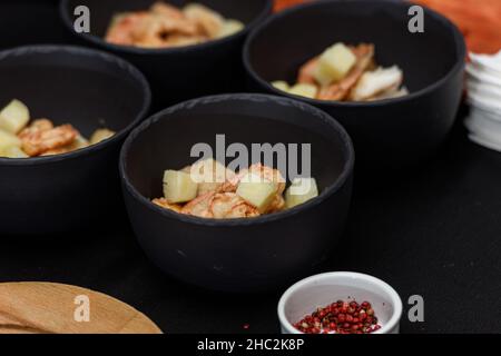 Processus de cuisson de la soupe Suquet de Peix aux pommes de terre, aux herbes et au poisson avec ajout de picada gros plan dans une casserole sur la table. Banque D'Images