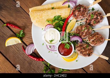 Kofta délicieux kebab (boulettes) avec la sauce et les tacos tortillas sur une assiette blanche. Vue d'en haut Banque D'Images