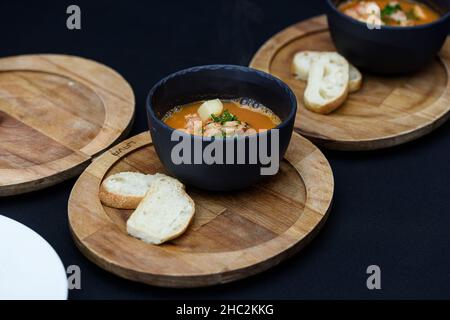 Soupe épicée de fruits de mer avec pommes de terre, crevettes, herbes et poisson d'une picade de gros plan dans une casserole servie avec du pain grillé. Horizontal Banque D'Images