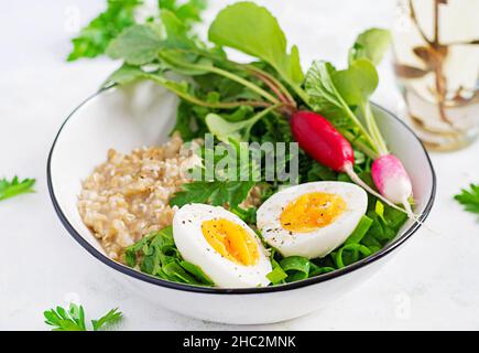 Petit déjeuner porridge de flocons d'avoine avec œufs durs, radis et herbes vertes. Une alimentation saine et équilibrée. Banque D'Images