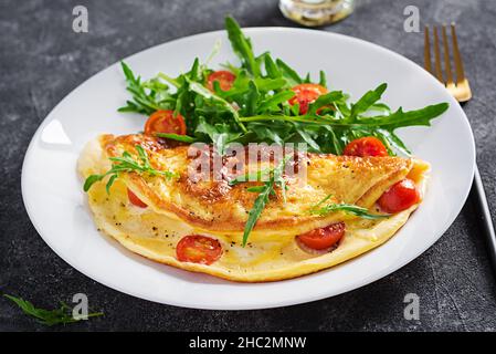 Petit déjeuner. Omelette avec tomates, fromage et salade sur plaque blanche. Frittata - omelette italienne. Banque D'Images