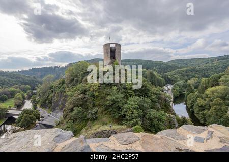 Tour ronde avec un mur détruit sur une montagne aux arbres luxuriants, entourée par la rivière et les collines en arrière-plan, le château en ruines d'Esch-sur-su Banque D'Images