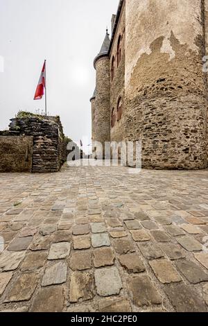 Vianden, Luxembourg.25 septembre 2021.Couloir extérieur avec sol en pierre entre les murs en pierre du château et la clôture avec drapeaux et une tour Banque D'Images