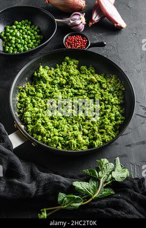 recette de petits pois anglais, poêle à frire cuite et petits pois dans un bol avec du poivre d'échalote à la menthe et du sel sur la surface de pierre noire, vue latérale de la nourriture de céto organique. Banque D'Images